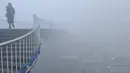 Warga berjalan melewati jembatan dengan kabut tebal akibat polusi udara yang kurang baik di Fuyang, Provinsi Anhui, China, (3/1). Kabut tebal ini membuat sejumlah warga mengunakan masker saat beraktivitas. (China Daily/via Reuters)