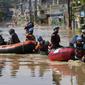 Warga duduk dalam perahu karet saat mereka mengungsi ke tempat yang lebih tinggi selama banjir di Bekasi, Jawa Barat, Kamis (17/2/2022). Hujan deras yang dikombinasikan dengan perencanaan pembuangan limbah kota yang buruk sering menyebabkan banjir besar. (AP Photo/Achmad Ibrahim)