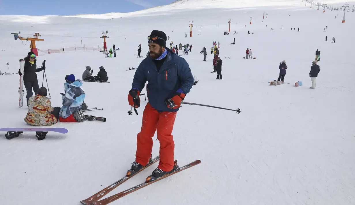 Seorang pemain ski menuruni lereng di resor ski Tochal di luar ibu kota Teheran, Iran (1/1/2022). Di tengah polusi udara dan kesengsaraan ekonomi, penduduk Teheran menemukan kenyamanan di resor ski di utara Teheran di pegunungan Alborz. (AP Photo/Vahid Salemi)