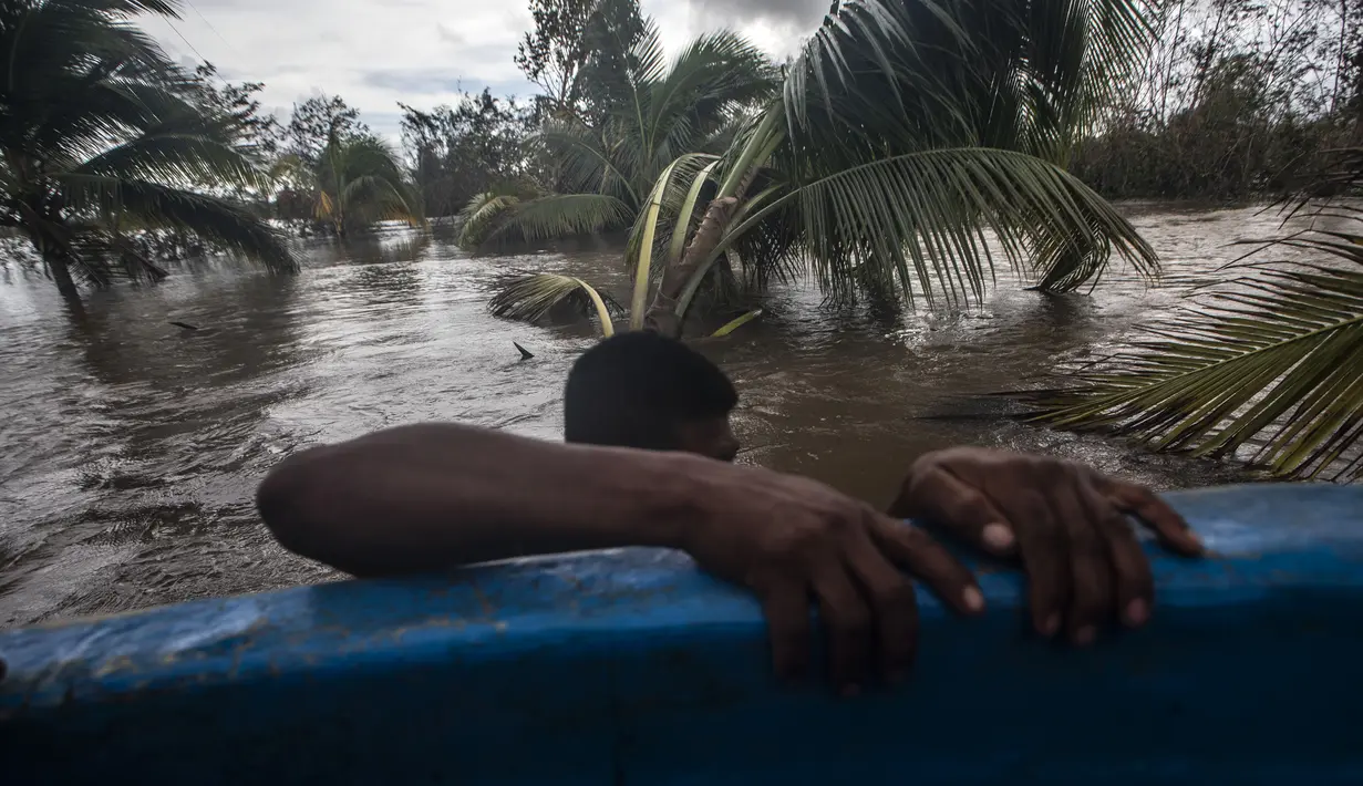 Seorang pria menarik kano di daerah banjir yang disebabkan oleh Sungai Wawa Boom setelah melintas Badai Iota di Bilwi, Puerto Cabezas, Nikaragua (18/11/2020). Badai Iota telah menewaskan sedikitnya sembilan orang saat menghancurkan rumah, menumbangkan pohon dan menggenangi air. (AFP/Inti Ocon)