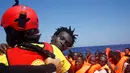 Seorang imigran diselamatkan dari perahu kayu yang disesaki ratusan imigran, di lepas panti Libya, Laut Mediterania, Senin (29/8). Para penjaga pantai Italia berhasil menyelamatkan sekitar 6.500 imigran dari Eritrea dan Somalia. (REUTERS/Giorgos Moutafis)