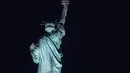 Bulan purnama, yang dikenal sebagai bulan stroberi, muncul di belakang Patung Liberty di New York City, Kamis (24/6/2021). Juni akan menandai kemunculan supermoon terakhir di 2021 yang juga disebut sebagai strawberry supermoon atau bulan purnama Stroberi. (Angela Weiss / AFP)