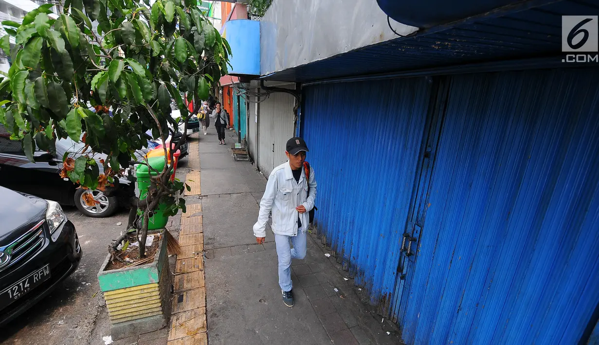 Pejalan kaki melintas di depan pertokoan yang tutup di Jalan Sabang, Jakarta pada Rabu (22/5/2019). Pemilik toko dan pengelola kantor di kawasan tersebut menutup toko dan kantor mereka imbas aksi 22 Mei 2019 yang berakhir rusuh di beberapa titik lokasi. (Liputan6.com/Aangga Yuniar)