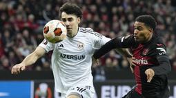 Pemain Bayer Leverkusen, Amine Adli (kanan) berusaha merebut bola dari pemain Qarabag, Behlul Mustafazade saat laga leg kedua 16 besar Liga Europa 2023/2024 di BayArena, Leverkusen, Jerman, Jumat (15/03/2024) dini hari WIB. (AP Photo/Martin Meissner)
