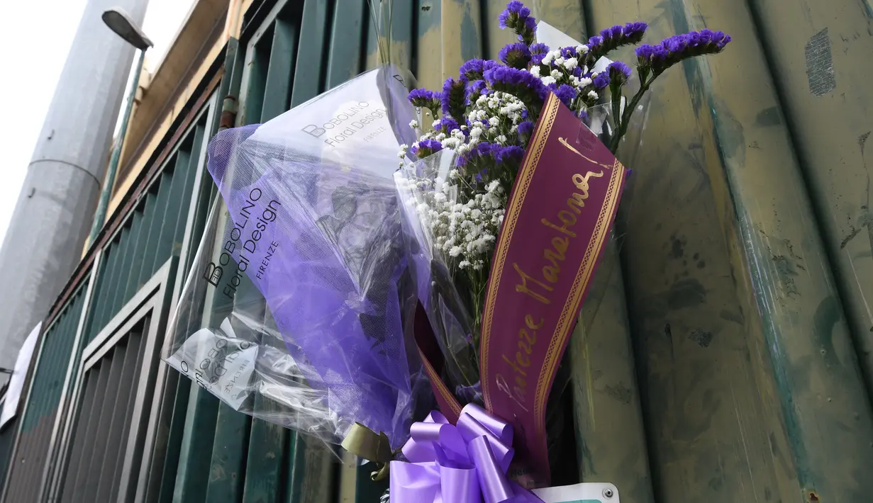 Penggemar menggantung buket bunga di pagar luar Stadion Artemio Franchi di Florence, Minggu (4/3). Fans melakukan aksi belasungkawa mengenang sosok kapten Fiorentina Davide Astori yang meninggal pada usai 31 tahun dalam tidurnya. (Claudio GIOVANNINI/AFP)