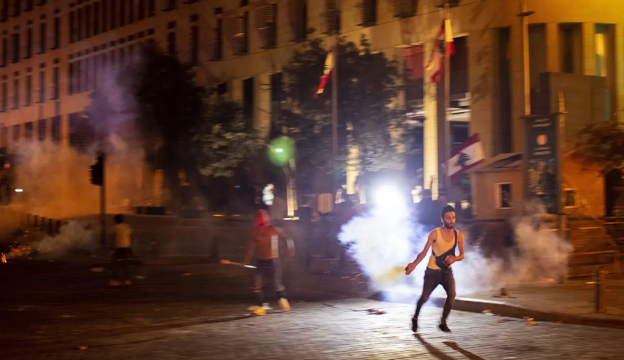 Seorang pengunjuk rasa antipemerintah melemparkan kembali tabung gas air mata ke arah polisi antihuru-hara selama protes terhadap elite politik yang telah memerintah negara selama beberapa dekade di Beirut, Lebanon, Jumat (7/8/2020). (AP Photo/Hassan Ammar )