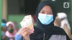 Warga penerima menunjukkan uang Bantuan Sosial Tunai (BST) bulan Januari di halaman Masjid Jami Al-Hidayah RW 01 Bedahan, Depok, Selasa (16/2/2021). Sekitar 159.470 Keluarga Penerima Manfaat (KPM) di Kota Depok menerima BST yang disalurkan PT Pos Indonesia pada Februari ini (merdeka.com/Arie Basuki)