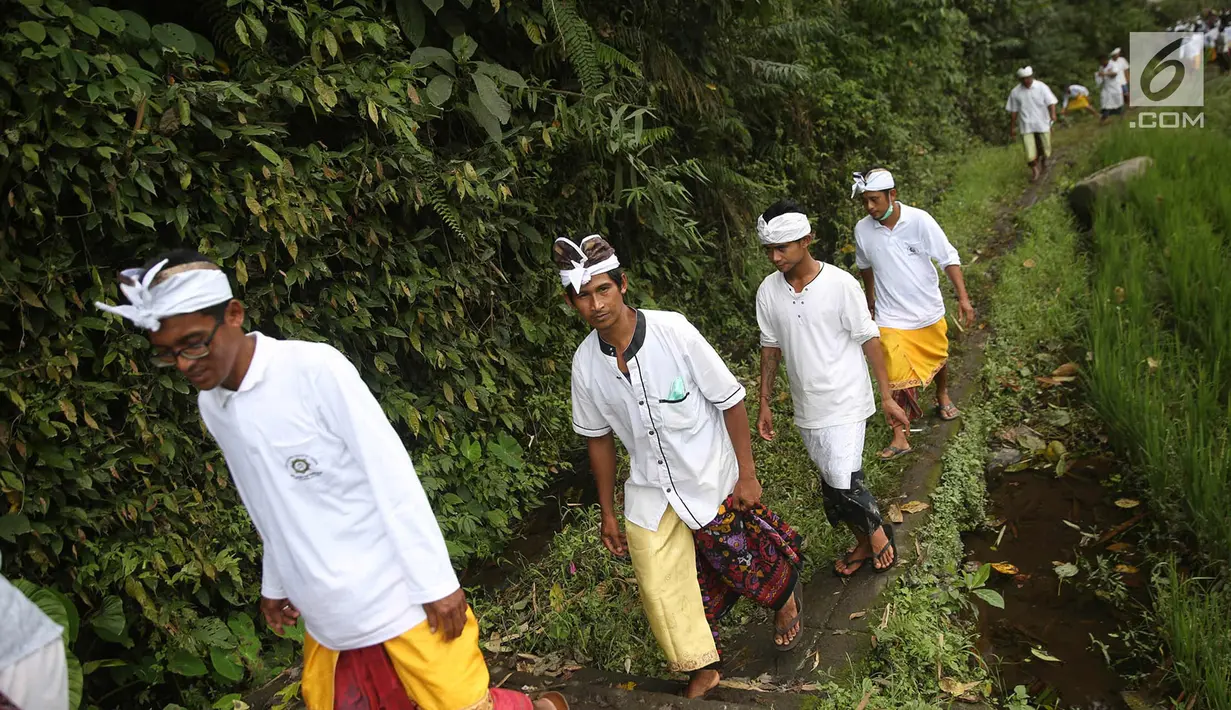 Warga berjalan untuk beribadah di sekitar Sungai Yeh Sah, Desa Batusesa, Kec Rendang, Karangasem, Bali, Jumat (1/12). Warga berharap diberi keselamatan dan berkah dari erupsi Gunung Agung yang terjadi. (Liputan6.com/Immanuel Antonius)