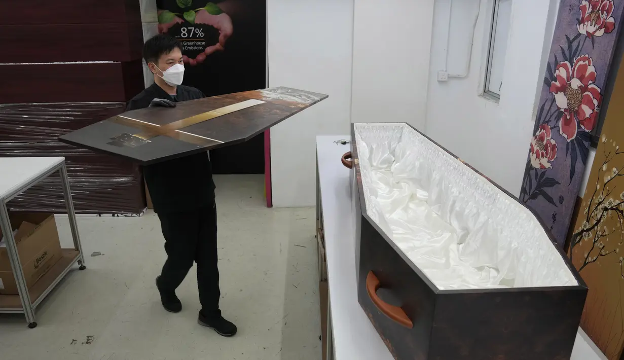 Seorang pekerja meletakkan penutup di atas peti mati kertas di pabrik LifeArt di Hong Kong, Jumat, 18 Maret 2022. LifeArt, sebuah perusahaan di Hong Kong sedang mencoba membuat alternatif peti mati dari kardus yang diklaim ramah lingkungan. (AP Photo/Kin Cheung)