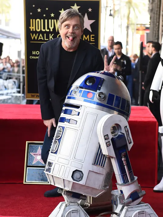 Pemeran Luke Skywalker dalam film "Star Wars", Mark Hamill berpose dengan karakter droid R2-D2 saat upacara pemberian Hollywood Walk of Fame di Los Angeles (8/3). (Jordan Strauss / Invision / AP)