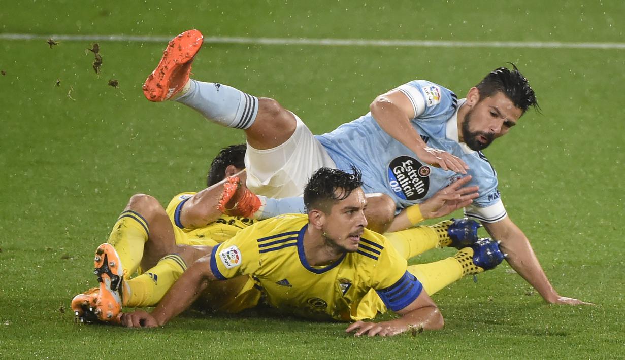 Penyerang Celta Vigo, Nolito, terjatuh saat berebut bola dengan pemain Cadiz pada laga lanjutan Liga Spanyol di Stadion Abanca Balaidos, Selasa (15/12/2020) dini hari WIB. Celta Vigo menang telak 4-0 atas Cadiz. (AFP/Miguel Riopa)
