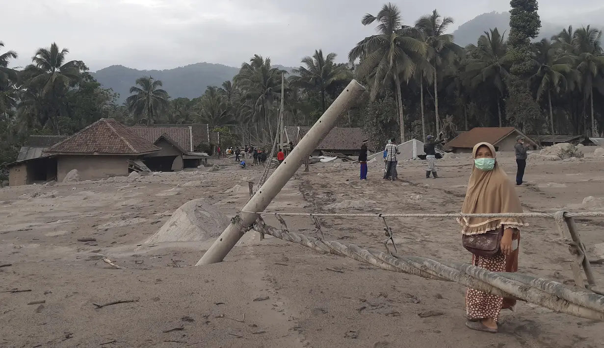 Seorang wanita berjalan di daerah yang terkena dampak erupsi Gunung Semeru di Lumajang, Jawa Timur, 5 Desember 2021. Akses jalan menuju lokasi pengungsi masih tertutup hujan yang disertai abu vulkanik Gunung Semeru yang masih cukup tebal. (AP Photo/Rokhmad)