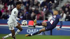 Penyerang Paris Saint-Germain (PSG) Kylian Mbappe menendang bola di sebelah bek Rennes, Warmed Omari pada  Ligue 1 2022/2023 pekan ke-28 di Parc des Princess, Senin (20/3/2023). (AP Photo/Christophe Ena)
