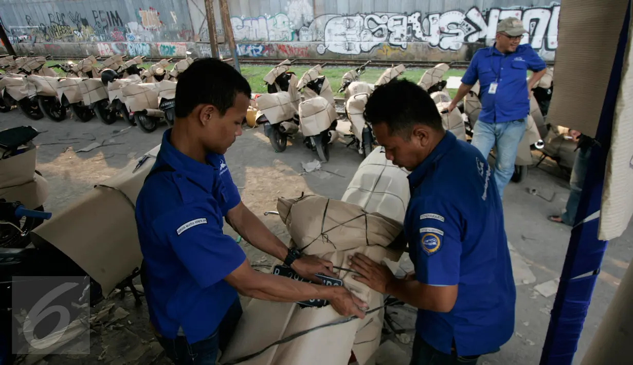 Petugas saat mengikat lapisan pembungkus motor pemudik yang akan di berangkatkan dari stasiun Lempuyangan,Yogyakarta, (11/7). Ratusan sepeda motor di angkut ke Jakarta pada arus balik lebaran 2016 tanpa di pungut biaya .(Boy Harjanto)