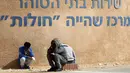 Migran Afrika duduk di sebelah pusat penahanan terbuka Holot sebelum melakukan aksi protes di Penjara Saharonim, Israel (22/2). Jika para migran Afrika tersebut tidak meninggalkan Israel, merekan akan mendekam di penjara. (AFP Photo/Menahem Kahana)