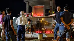 Sebuah keluarga Sino-Guianese berdiri di sekitar sebuah makam yang dihiasi bunga dan lilin di pemakaman Cayenne di Guyana Prancis (1/11). Perayaan ini adalah satu hari sebelum perayaan Peringatan Arwah Semua Orang Beriman. (AFP Photo/Jody Amiet)