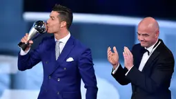 Cristiano Ronaldo saat mencium The Best FIFA Men's Player of 2016 Award yang diberikan Presiden FIFA Gianni Infantino pada ajang The Best FIFA Football Awards 2016  di Zurich, (9/1/2017). (AFP/Fabrice Coffrini)