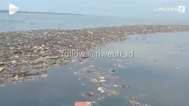 Seorang warga merekam keadaan lautan di sekitar Pulau Pari, Kepulauan Seribu yang penuh sampah berbau busuk dan tercampur limbah aspal.