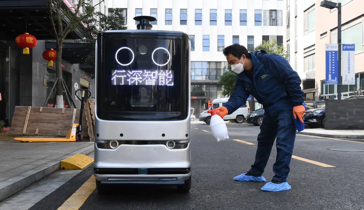 Seorang staf menyemprotkan disinfektan pada robot pengiriman setelah mengantar makanan di Changsha, China, 14 Februari 2020. Dua robot pengiriman dialihfungsikan untuk mengantar makan siang dan makan malam bagi para karyawan di perusahaan yang melanjutkan produksi di kawasan itu. (Xinhua/Xue Yuge)