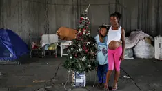 Tatiani (kanan) dan anaknya Leonardo berpose disamping pohon Natal di Sao Paulo, Brasil, (18/12). Mereka adalah keluarga tunawisma yang tinggal di bawah jembatan. (REUTERS/Nacho Doce)