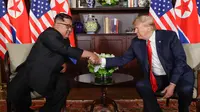 Presiden Amerika Serikat (AS) Donald Trump  dan Pemimpin Korea Utara, Kim Jong-un bersalaman dalam pertemuan bersejarah di resor Capella, Pulau Sentosa, Selasa (12/6). Trump dan Kim menyempatkan diri untuk menyapa jurnalis. (AP/Evan Vucci)