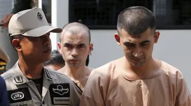 Dua tersangka pemboman Yusufu Mieraili dan Bilal Mohammed berjalan saat tiba di Pengadilan militer (20/4). Yusufu dan Bilal didakwa terkait pemboman sebuah kuil di Bangkok yang terjadi pada 17 Agustus 2015 lalu. (REUTERS/Chaiwat Subprasom)