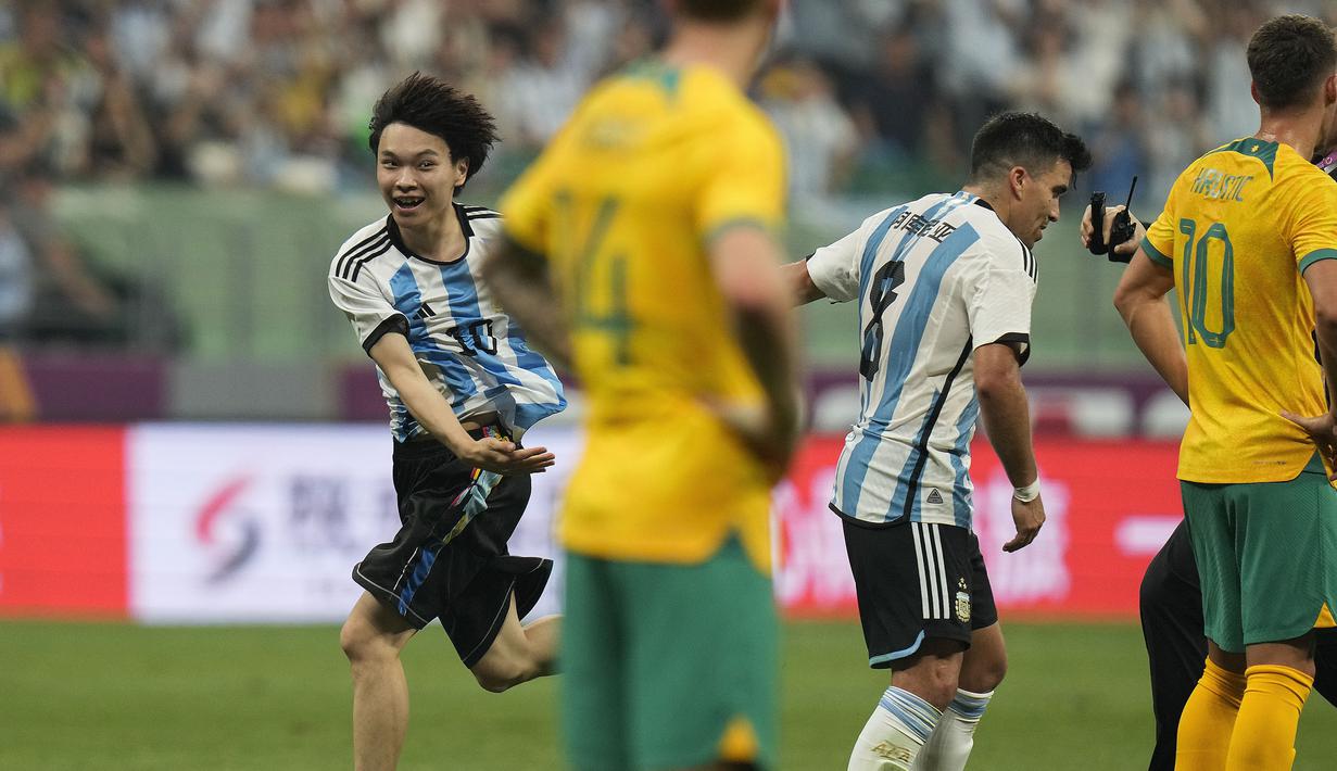 Seorang penyusup lapangan berlari melewati pemain Argentina, Marcus Acuna pada laga persahabatan antara Argentina melawan Australia di Workers' Stadium, Beijing, Kamis (15/06/2023). (AP Photo/Andy Wong)