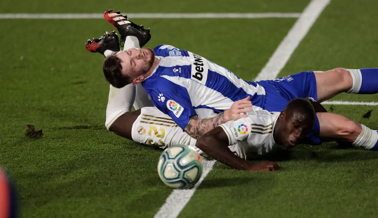 Pemain Alaves, Oliver Burke dan bek Real Madrid, Ferland Mendy terjatuh saat berebut bola pada lanjutan Liga Spanyol di stadion Alfredo di Stefano, Sabtu (11/7/2020). Real Madrid menang 2-0 lewat gol Karim Benzema dan Marco Asensio. (AP Photo/Bernat Armangue)