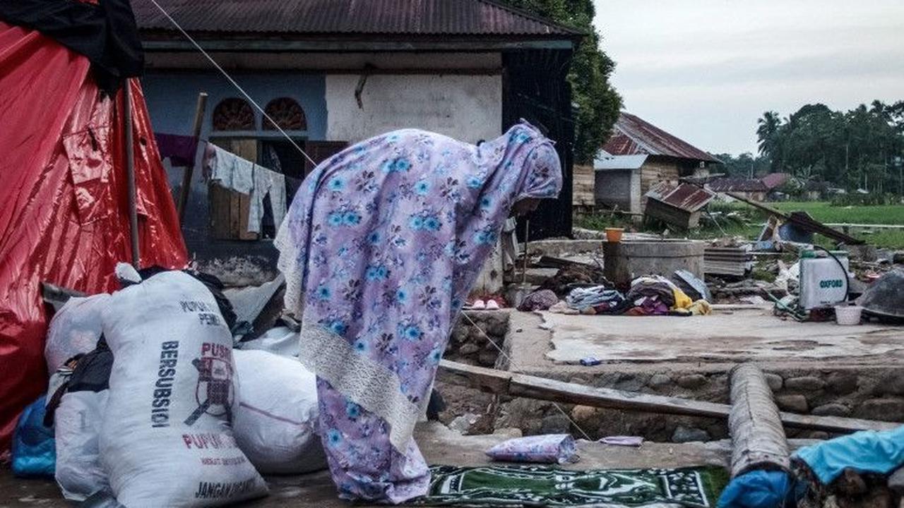Seorang warga menunaikan ibadah salat maghrib seusai berbuka puasa Ramadan di dekat puing bangunan yang runtuh akibat terjangan banjir bandang di Ganting, Pesisir Selatan, Sumatera Barat, pada 14 Maret 2024. Terjangan banjir bandang di Ganting, Pesisir Se