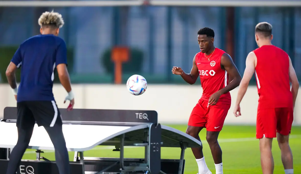 Pemain Kanada Jonathan David (tengah) menendang bola saat bermain sepak bola dengan rekan setimnya menggunakan permukaan tenis meja saat latihan di Doha, Qatar, 29 November 2022. Kanada akan menghadapi Maroko dalam pertandingan Piala Dunia 2022 pada 1 Desember 2022. (Nathan Denette/The Canadian Press via AP)