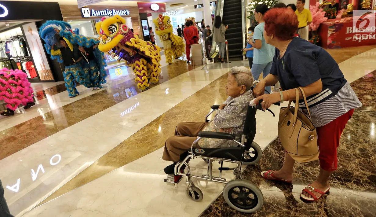 Pengunjung duduk di kursi roda sambil menyaksikan parade barongsai pada perayaan Cap Go Meh di Pluit Village, Jakarta Utara, Jumat (02/3). Sebanyak 50 barongsai hibur pengunjung sebagai tanda berakhirnya perayaan Imlek. (Liputan6.com/Fery  Pradolo)