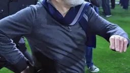 Presiden PAOK Ivan Savvidis turun ke lapangan dengan pistol di pinggangnya saat Liga Super Yunani di Stadion Toumbas, Minggu (11/3). Savvidis memprotes wasit yang membatalkan gol PAOK yang dicetak Fernando Valera pada menit ke-89. (InTime Sports via AP)