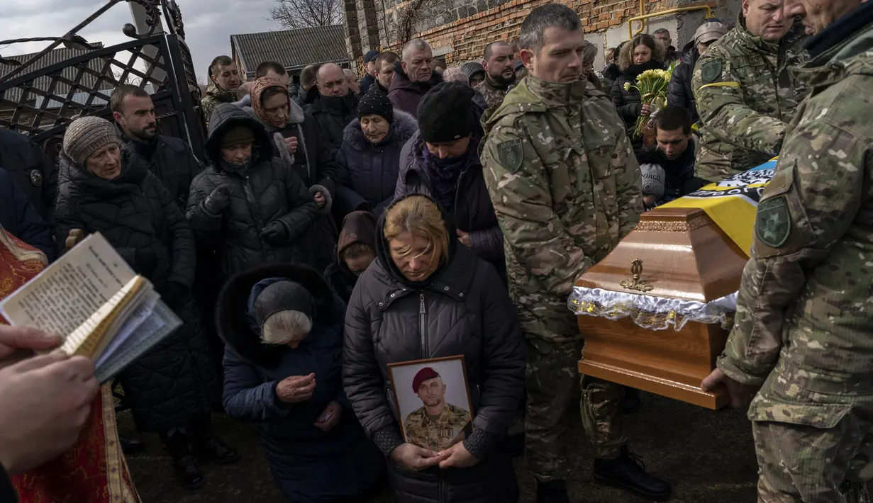 Kerabat dan teman berkabung di pemakaman sersan polisi senior Roman Rushchyshyn di desa Soposhyn, pinggiran Lviv, Ukraina barat, Kamis, 10 Maret 2022. Rushchyshyn, seorang anggota Batalyon Patroli Polisi Khusus Lviv, terbunuh di Wilayah Luhansk. (AP Photo/Bernat Armangue)