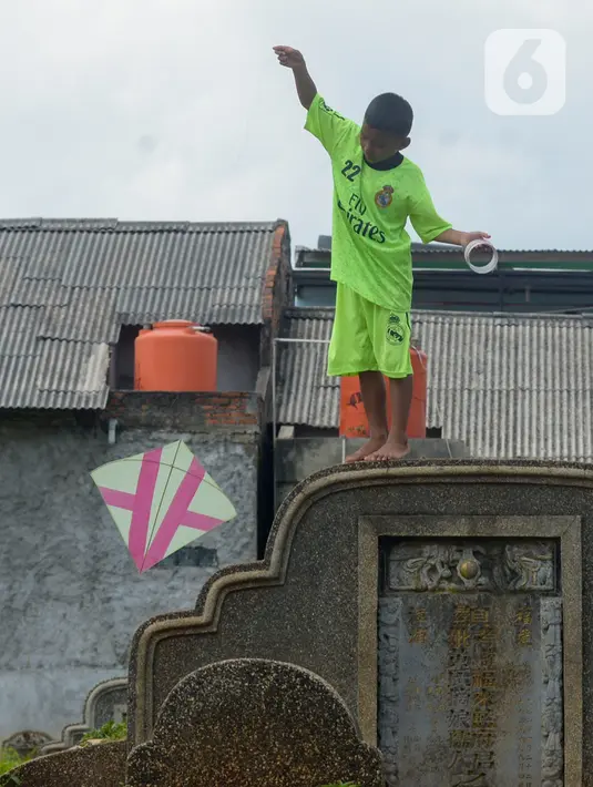 Anak-anak menerbangkan layang-layang di Tanah Makam Cipinang Besar Utara, Jakarta, Selasa (14/1/2020). Pemprov DKI Jakarta berencana terus menambah Ruang Publik Terpadu Ramah Anak (RPTRA) di sejumlah wilayah. (merdeka.com/Imam Buhori)