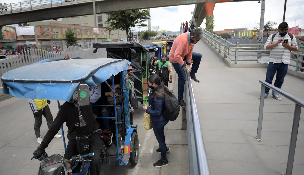 Seorang pria melompati rel untuk menggunakan bicitaxi sebagai alternatif transportasi setelah penghancuran beberapa stasiun layanan umum selama protes terhadap pemerintah Presiden Kolombia Ivan Duque, di Bogota (24/5/2021). (AFP/ Raul Arboleda)