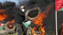 Seorang demonstran membakar ban saat protes terhadap serangan militer Israel ke Kota Nablus, Tepi Barat, di sepanjang pagar perbatasan dengan Israel di sebelah timur Kota Gaza, 22 Februari 2023. Para pejabat Palestina mengatakan sejumlah warga Palestina telah terbunuh dan lebih dari seratus orang terluka dalam serangan tentara Israel yang jarang terjadi di Tepi Barat. (AP Photo/Adel Hana)