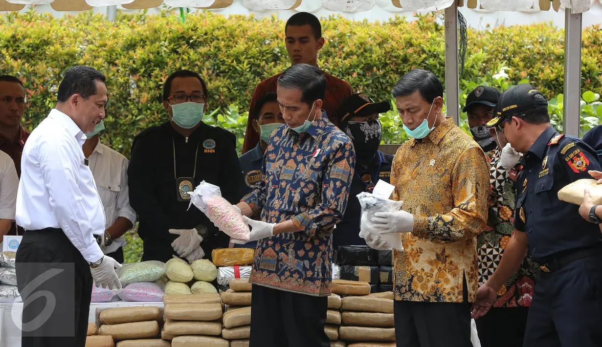 Presiden Jokowi mengamati barang bukti narkoba hasil rampasan BNN di Monas, Jakarta, Selasa (6/12). Pemusnahan terdiri dari 445 kg sabu, 190 ribu butir ekstasi, 422 kg ganja kering dan 323 ribu butir happy five. (Liputan6.com/Faizal Fanani)