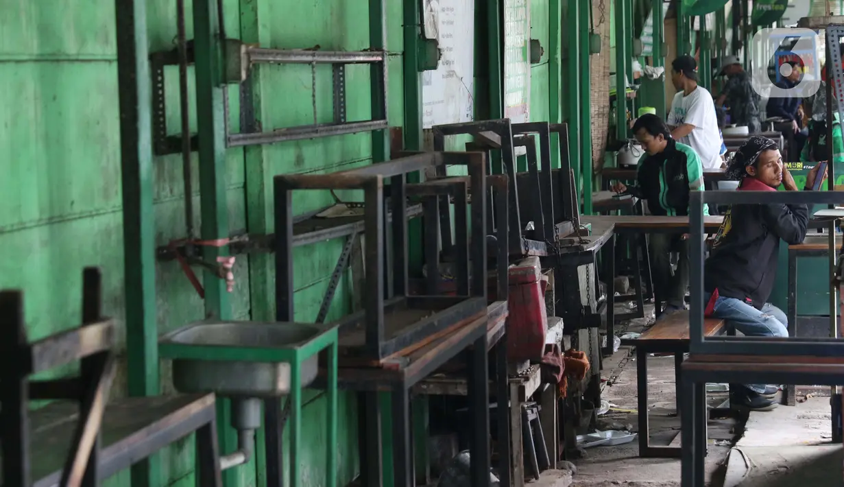 Pengemudi ojek daring di warung kaki lima yang tutup di kawasan Kuningan, Jakarta, Kamis (2/4/2020). Minimnya aktivitas perkantoran di Jakarta akibat pandemi COVID-19 membuat sejumlah pedagang warung kaki lima memilih menutup dagangannya karena sepi pembeli. (Liputan6.com/Helmi Fithriansyah)