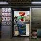 Seorang pegawai minimarket 7-Eleven yang biasanya buka 24 jam mengunci pintu gerai jelang pembatasan jam malam untuk mengurangi penyebaran COVID-19 di Bangkok, Thailand, Senin (19/7/2021). Jumlah kematian akibat COVID-19 di Thailand mencapai 3.610 kasus sejak pandemi dimulai. (Candida NG/AFP)