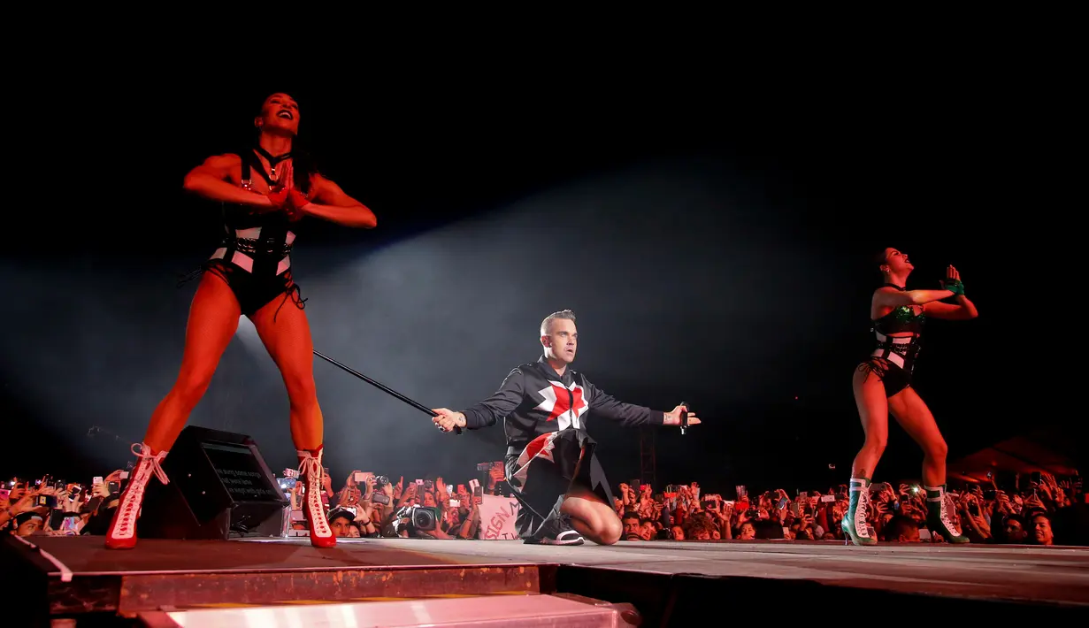 Aksi panggung Robbie Williams bersama para penari di Festival Musik Corona Capital di Meksiko (17/11). Pria 44 tahun ini tampil energik mengenakan setelan jas hitam dan rok yang dihiasi bintang merah. (AP Photo/Eduardo Verdugo)