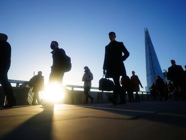 Komuter melintasi London Bridge untuk bekerja menuju kantor di London, Kamis (20/1/2022). Pemerintah Inggris mengakhiri pembatasan COVID-19, termasuk mandat masker, bekerja dari rumah dan paspor vaksin mulai Kamis. (AP Photo/Kirsty Wigglesworth)