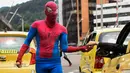 Jahn Fredy Duque menerima uang usai aksi di jalanan Bogota, Kolombia, Senin (24/4). Duque mencari nafkah dengan melakukan atraksi layaknya Spiderman. (AFP Photo/RAUL ARBOLEDA)