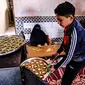 Anggota keluarga Palestina menyiapkan kue-kue tradisional untuk dijual sebagai persiapan liburan Idul Fitri mendatang, di kota Rafah, Jalur Gaza, Selasa (4/5/2021). Pembuatan kue tradisional untuk Hari Raya Idul Fitri atau Lebaran yang akan datang menandai akhir bulan Ramadhan. (KATA KHATIB/AFP)