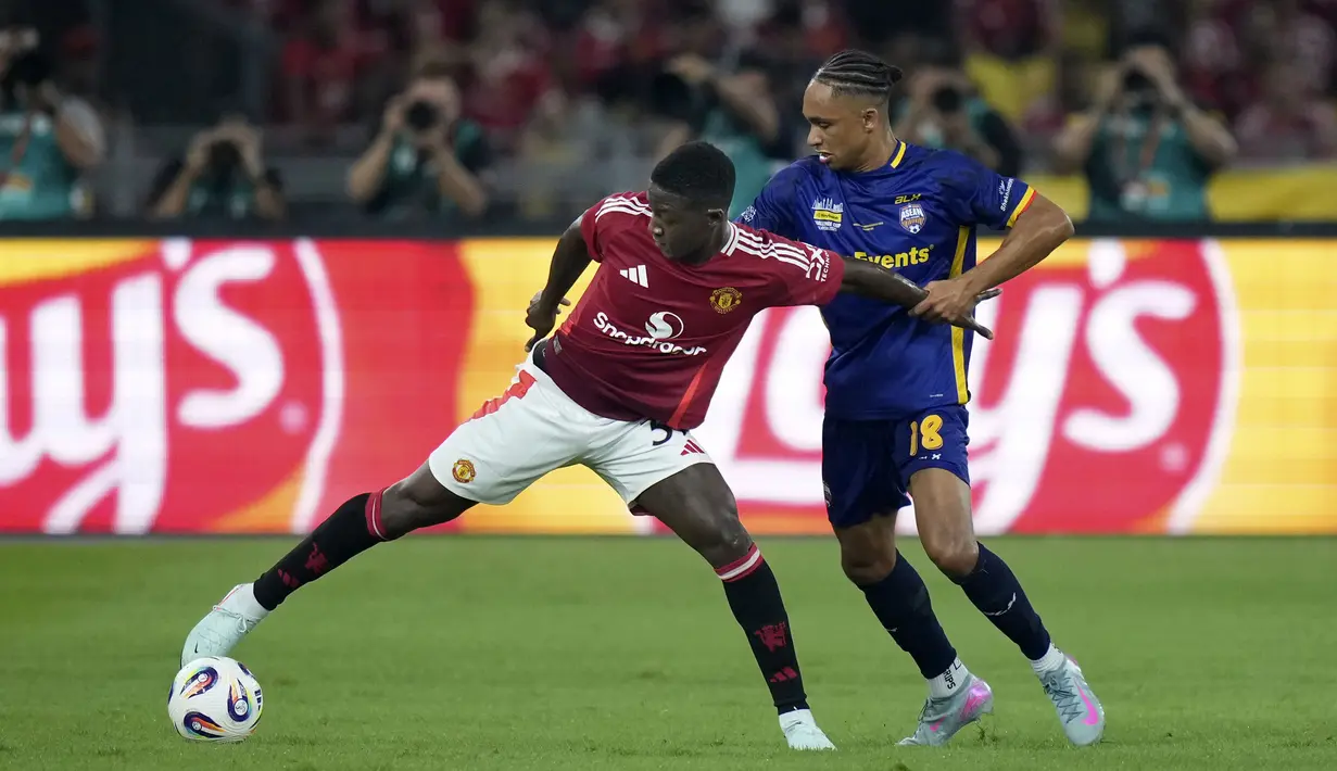 Pemain Manchester United, Kobbie Mainoo (kiri) berebut bola dengan pemain ASEAN All-Stars, Kealey Adamson dalam laga persahabatan yang berlangsung di Stadion Bukit Jalil, Malaysia, pada hari Rabu (28/5/2025) malam waktu setempat. (AP Photo/Vincent Thian)