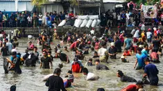 Ratusan warga menangkap ikan dengan tangan tangan kosong saat kegiatan Ngubek Empang di Jalan Abdul Ghani Raya, Kelurahan Kalibaru, Kecamatan Cilodong. Depok, Jawa Barat, Kamis (16/5/2024). (merdeka.com/Arie Basuki)