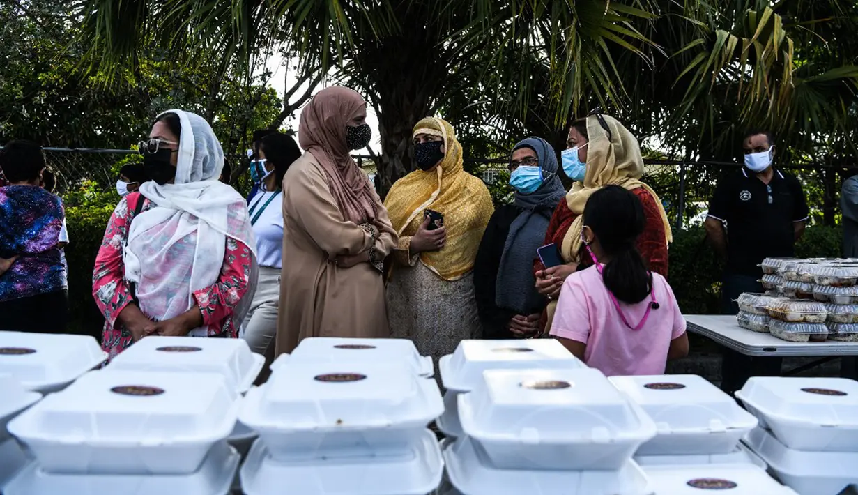 Para relawan Asosiasi Komunitas Muslim Miami dan Yayasan Lumba-Lumba Miami mendistribusikan makanan buka puasa Ramadhan di Miami Gardens, Florida, Amerika Serikat, Selasa (27/4/2021). Distribusi makanan dilakukan secara drive thru. (CHANDAN KHANNA/AFP)