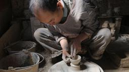 Seorang perajin bekerja di bengkel pembuatan tembikar di Desa Wanyao, Mazhan, Tengchong, Provinsi Yunnan, China, 18 November 2020. Produk tembikar dari desa ini memiliki bentuk yang sederhana namun praktis. (Xinhua/Liang Zhiqiang)