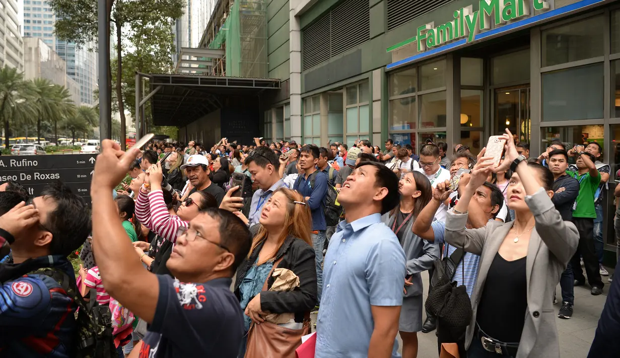 Warga menyaksikan aksi pendaki Prancis, Alain Robert memanjat Menara Internasional GT berlantai 47 di Makati City, Manila, Filipina (29/1). (AFP Photo/Ted Aljibe)