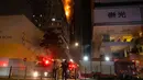 Petugas pemadam kebakaran memadamkan api di lokasi konstruksi di Hong Kong, Jumat (3/3/2023). Petugas pemadam kebakaran dan truk pemadam kebakaran terlihat di jalan-jalan di dekatnya saat api membubung dari atas gedung yang terbakar. (AP Photo/Louise Delmotte)