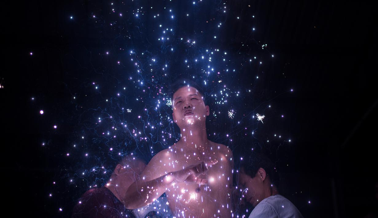 Ekpresi seorang pria yang dipercikan kembang api saat mengikuti ritual eating flowers di provinsi Fujians, China (16/2). Menurut seorang peserta, ia melakukan ritual tersebut guna meminta keselamatan bagi keluarganya. (AFP/Johannes Eisele)